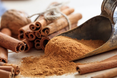 Cinnamon sticks and ground cinnamon in a scoop on a wooden surface